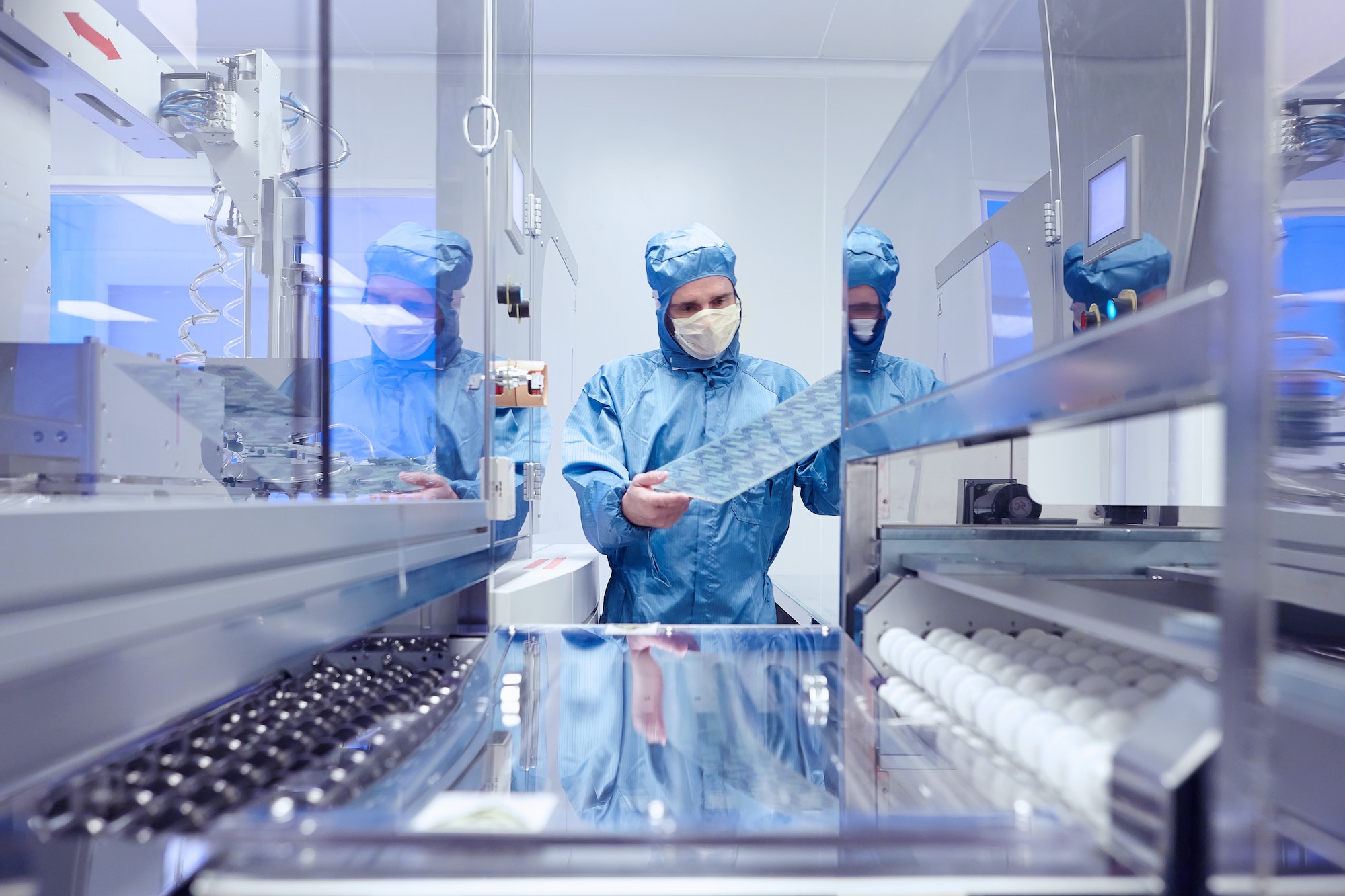 Male worker inspecting flex circuit in flexible electronics factory clean room